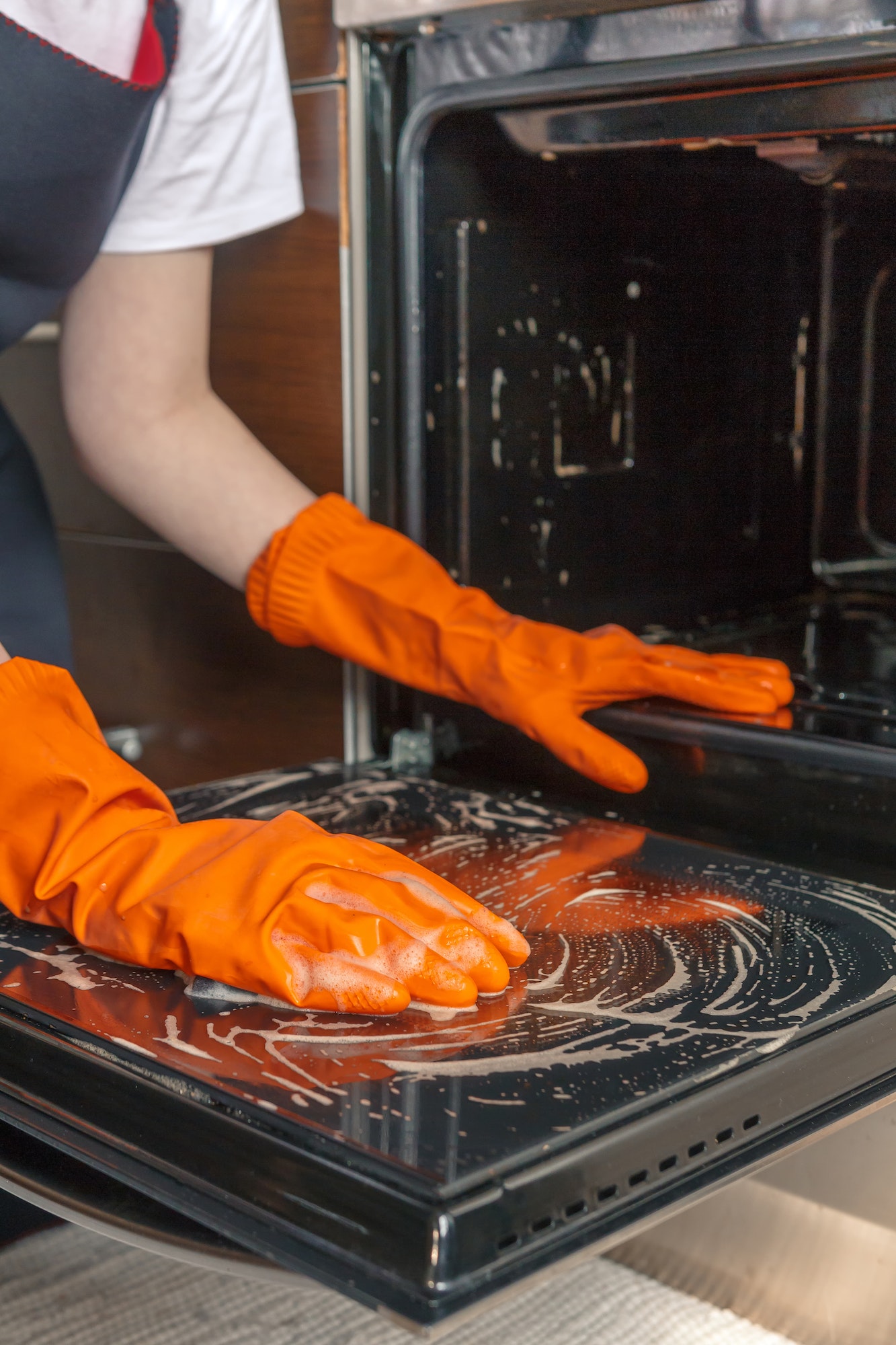 Kitchen cleaning. Girl's hands in gloves wash clean the stove, kitchen oven in the kitchen Deep oven clean